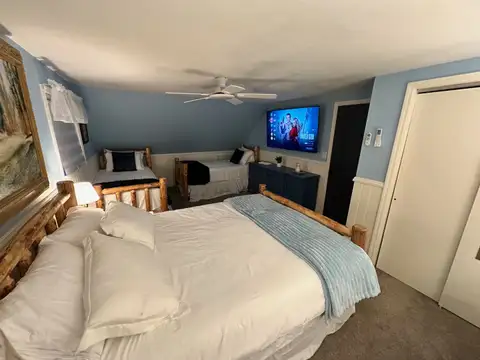 Bedroom 5 log-frame beds with white and light blue bedding, smart TV and coastal blue walls
