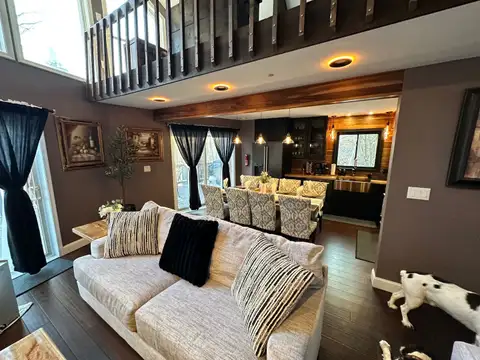 Cream sofa with striped pillows facing the dining table for eight and dark-cabinet kitchen beyond