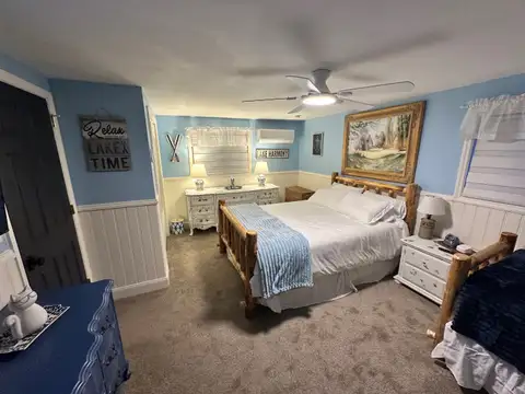 Lake-themed Bedroom 5 with rustic log king bed, blue accents, dressers and a 'Relax, you're on lake time' sign