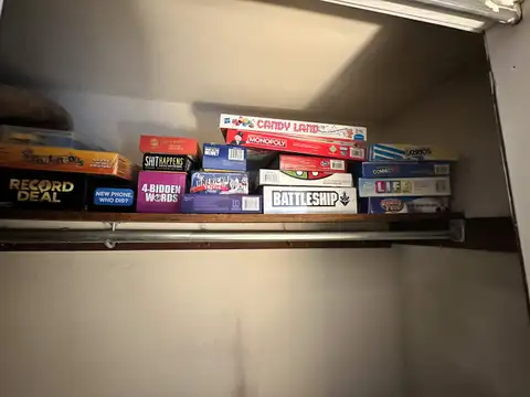 Closet shelf stocked with board games including Monopoly, Battleship, Candy Land, Sorry, Connect 4 and Life
