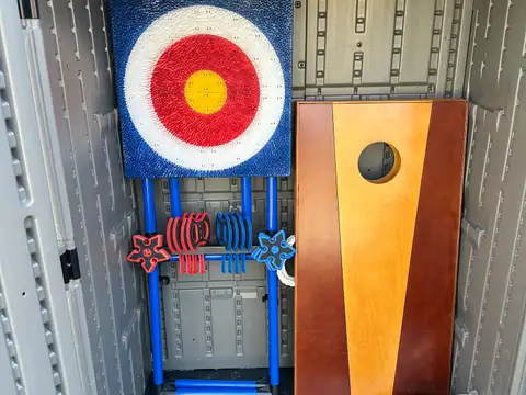 Outdoor game shed stocked with cornhole board, and ring-toss target set