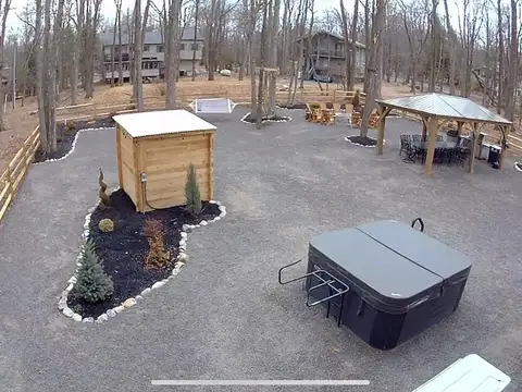 Aerial view of the fenced backyard with hot tub, cedar sauna, gazebo dining area and landscaped gravel grounds